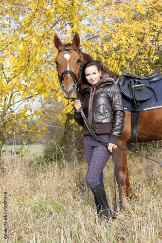 Photo: equestrian with her horse on autumnal meadow equestrian with her horse on autumnal meadow