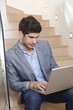Young man using laptop computer in stairway