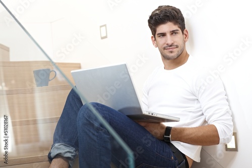 Photo: Happy man using laptop computer at home Happy man using laptop computer at home