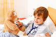 Foto: Krankes Kind untersucht Teddy mit Stethoskop Krankes Kind untersucht Teddy mit Stethoskop