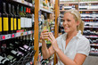 Frau beim Weinregal eines Supermarktes