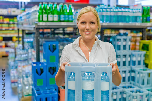 Photo: Frau kauft Mineralwasser im Supermarkt Frau kauft Mineralwasser im Supermarkt
