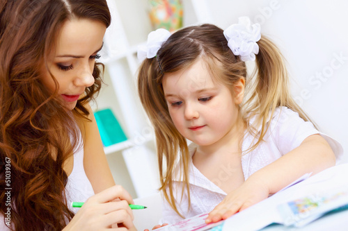 Photo: Little girl and her mother studying Little girl and her mother studying