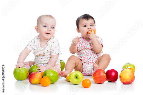 Photo: Funny kids babies eating healthy food fruits isolated on white Funny kids babies eating healthy food fruits isolated on white