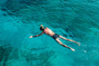 Young man with scuba equipment laying on sea surface