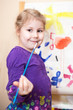 Photo: Happy preschool girl painting a picture with paints and brush Happy preschool girl painting a picture with paints and brush