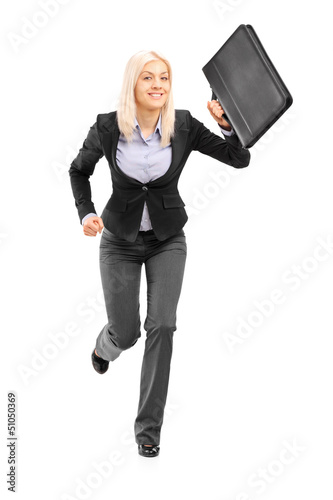 Photo: Businesswoman running with a briefcase and looking at camera Businesswoman running with a briefcase and looking at camera