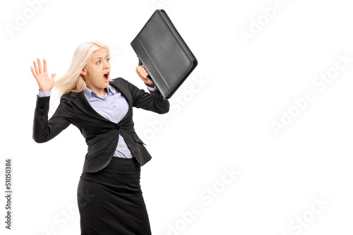 Photo: Scared young businesswoman protecting with briefcase and gesturi Scared young businesswoman protecting with briefcase and gesturi