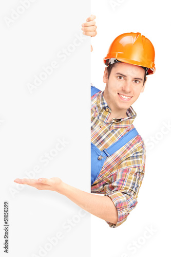 Photo: Young construction worker with helmet posing and gesturing on a Young construction worker with helmet posing and gesturing on a