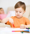 Little boy is drawing on white paper
