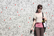 Foto: Young woman next to tile wall. Young woman next to tile wall.