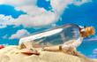 Glass bottle with note inside on sand, on blue sky background