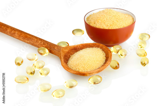 Photo: Gelatin in a bowl and wooden spoon on white background close-up Gelatin in a bowl and wooden spoon on white background close-up