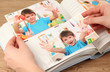 Photos in hands and photo album on wooden table