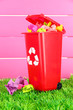 Photo: Recycling bin with papers on grass on pink background Recycling bin with papers on grass on pink background