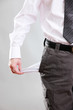 Business man showing his empty pocket, on grey background