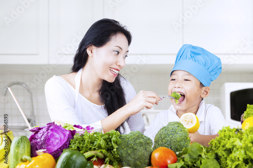 Photo: Mother feed brocolli to her child Mother feed brocolli to her child