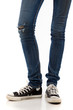 Photo: Legs with jeans and retro black sneakers on a white background Legs with jeans and retro black sneakers on a white background