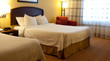 A hotel room with beds, chair and lamps