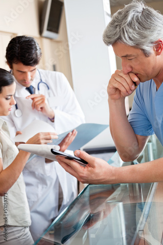 Photo: Doctor Reading Document At Reception Doctor Reading Document At Reception