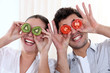 Funny couple covering their eyes with fruit