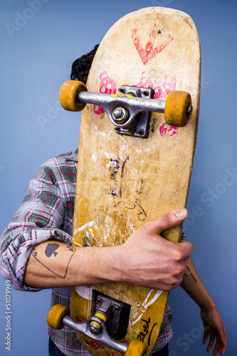 Photo: Skater hiding behind his skateboard Skater hiding behind his skateboard