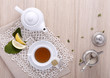 teapot with cup of tea, tea bag, lemon, sugar,