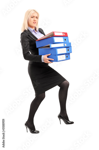 Photo: Full length portrait of a young professional woman holding folde Full length portrait of a young professional woman holding folde