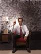Photo: young man in white shirt sitting on red sofa young man in white shirt sitting on red sofa