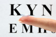 contact lens on finger, on snellen eye chart background