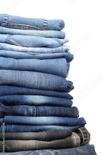 Photo: Many jeans stacked in a pile isolated on white Many jeans stacked in a pile isolated on white