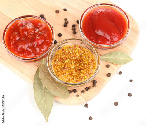 Photo: various sauces on chopping board isolated on white various sauces on chopping board isolated on white