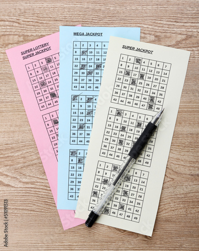 Photo: Lottery tickets and pen, on wooden background Lottery tickets and pen, on wooden background