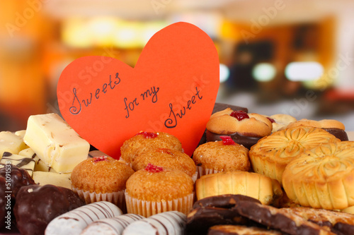 Photo: Sweet cookies with valentine card on table in cafe Sweet cookies with valentine card on table in cafe