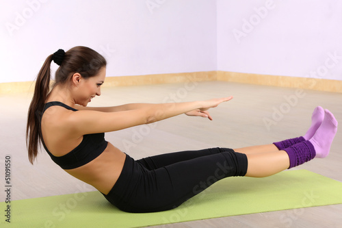 Photo: Young woman doing fitness exercises at gym Young woman doing fitness exercises at gym