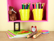 Colorful pencils in pails on shelf on beige background