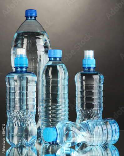 Photo: Different water bottles on grey background Different water bottles on grey background