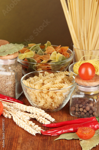 Photo: Different types of pasta, spices, tomatoes on a wooden table Different types of pasta, spices, tomatoes on a wooden table