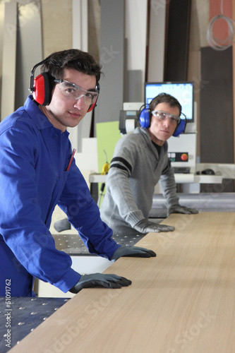 Photo: Two men working an industrial saw Two men working an industrial saw