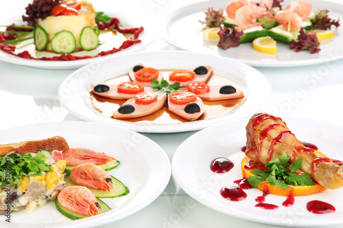 Photo: Small portions of food on big white plates close up Small portions of food on big white plates close up