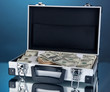 Suitcase with 100 dollar bills on blue background