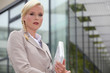 Businesswoman holding computer outside glass building