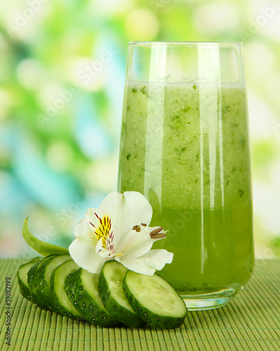 Photo: Glass of cucumber juice, on bamboo mat, on green background Glass of cucumber juice, on bamboo mat, on green background