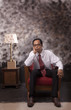 Photo: young man in white shirt sitting on red sofa young man in white shirt sitting on red sofa