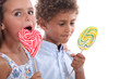 Photo: Closeup of two children eating lollipops Closeup of two children eating lollipops