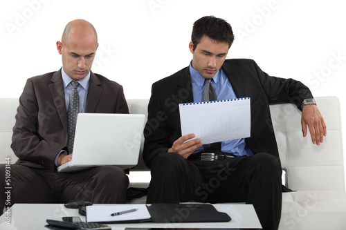 Photo: Two businessmen reading through presentation Two businessmen reading through presentation