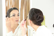 Brunette applying mascara in mirror