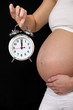 pregnant woman holding alarm clock