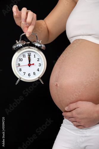 Photo: pregnant woman holding alarm clock pregnant woman holding alarm clock