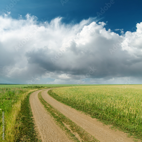 Photo: dirty road in fields and low clouds on horizon dirty road in fields and low clouds on horizon